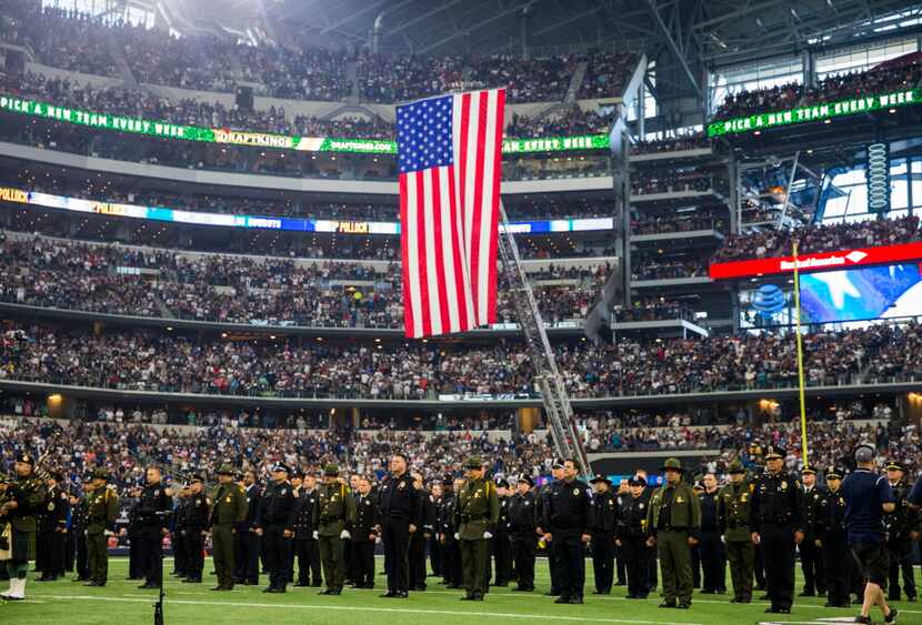 First responders stand at attention on the field during halftime of the Dallas Cowboys v....