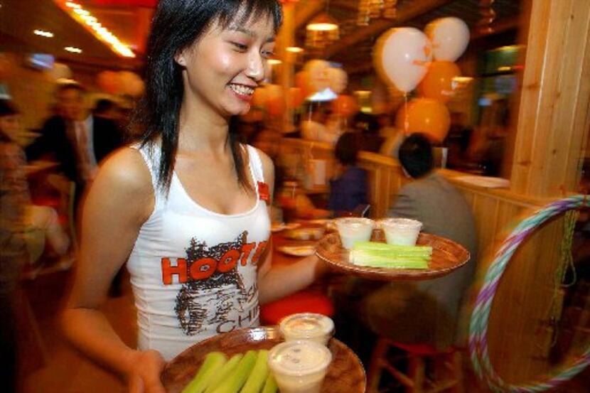 ORG XMIT: *S0410620909* A Chinese waitress brings dish during the pre-opening of Hooters ...