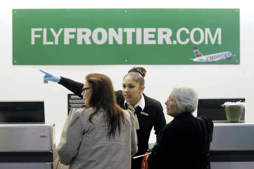 FILE - In this Oct. 15, 2014 file photo, a Frontier Airlines employee directs passengers at...