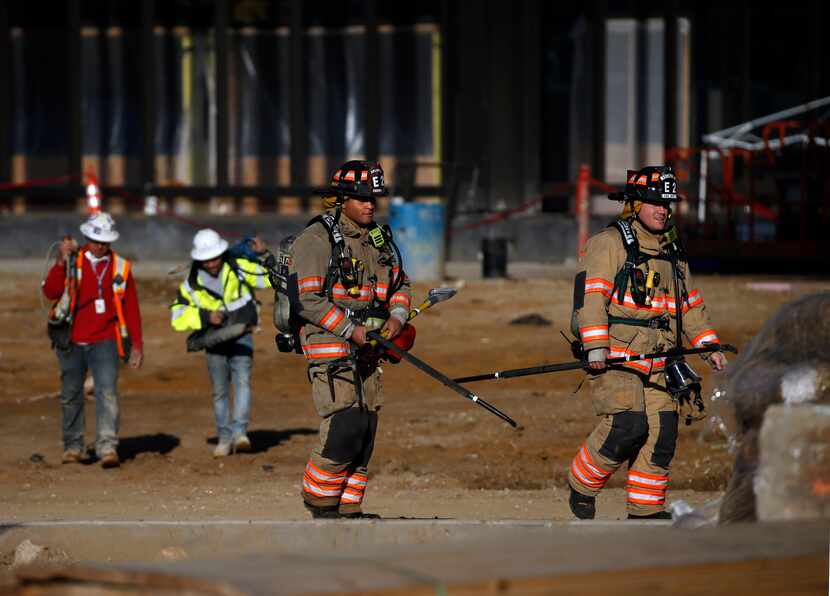 Arlington firefighters and construction workers leave the scene of a fire in the upper...
