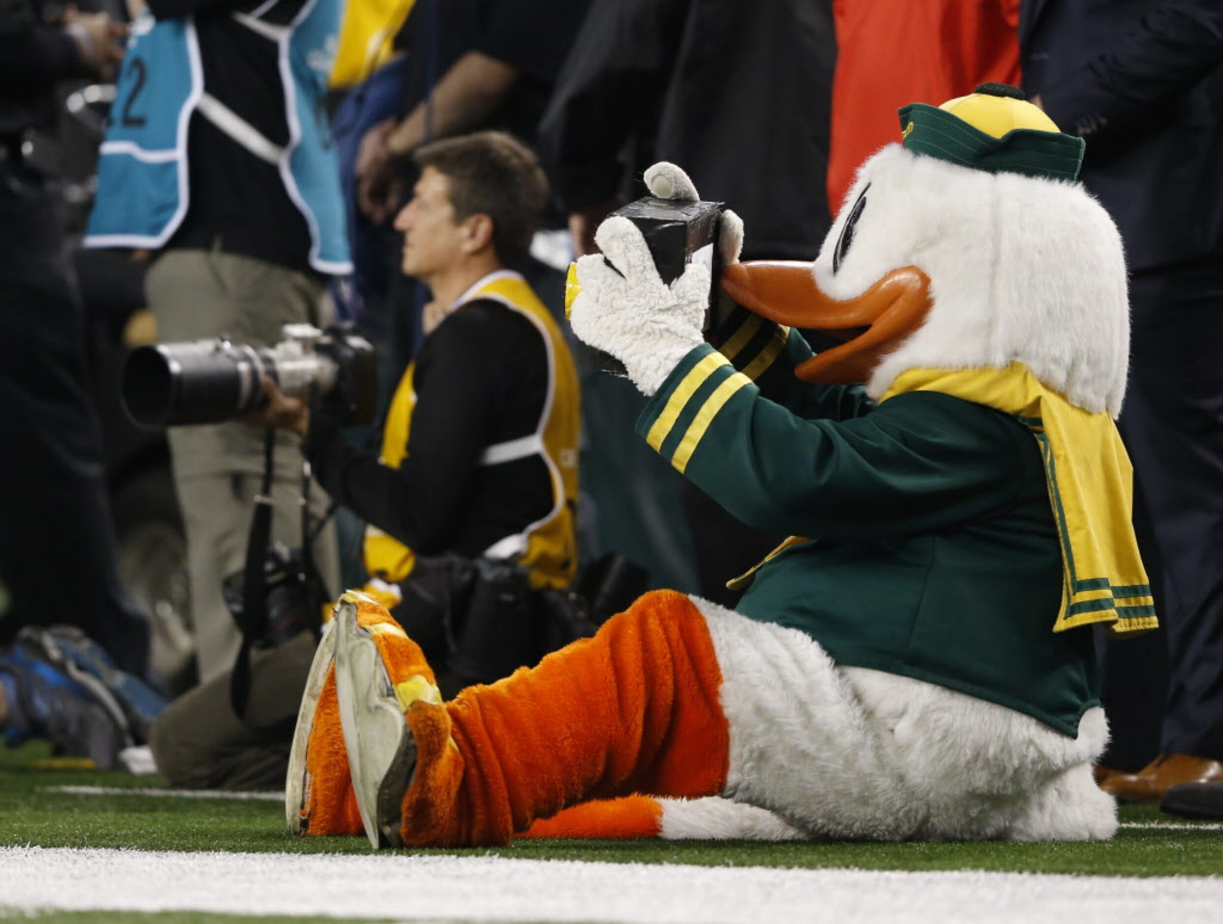 The Oregon Duck mimics taking photos from the sideline during the second half of the College...