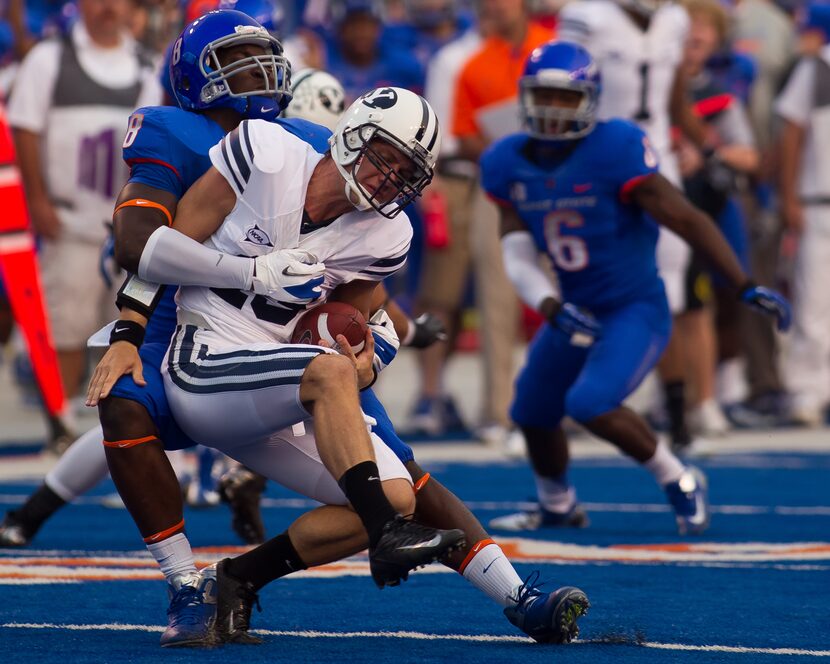 BOISE, ID - SEPTEMBER 20:  Riley Nelson #13 of the BYU Cougars is brought down by Demarcus...