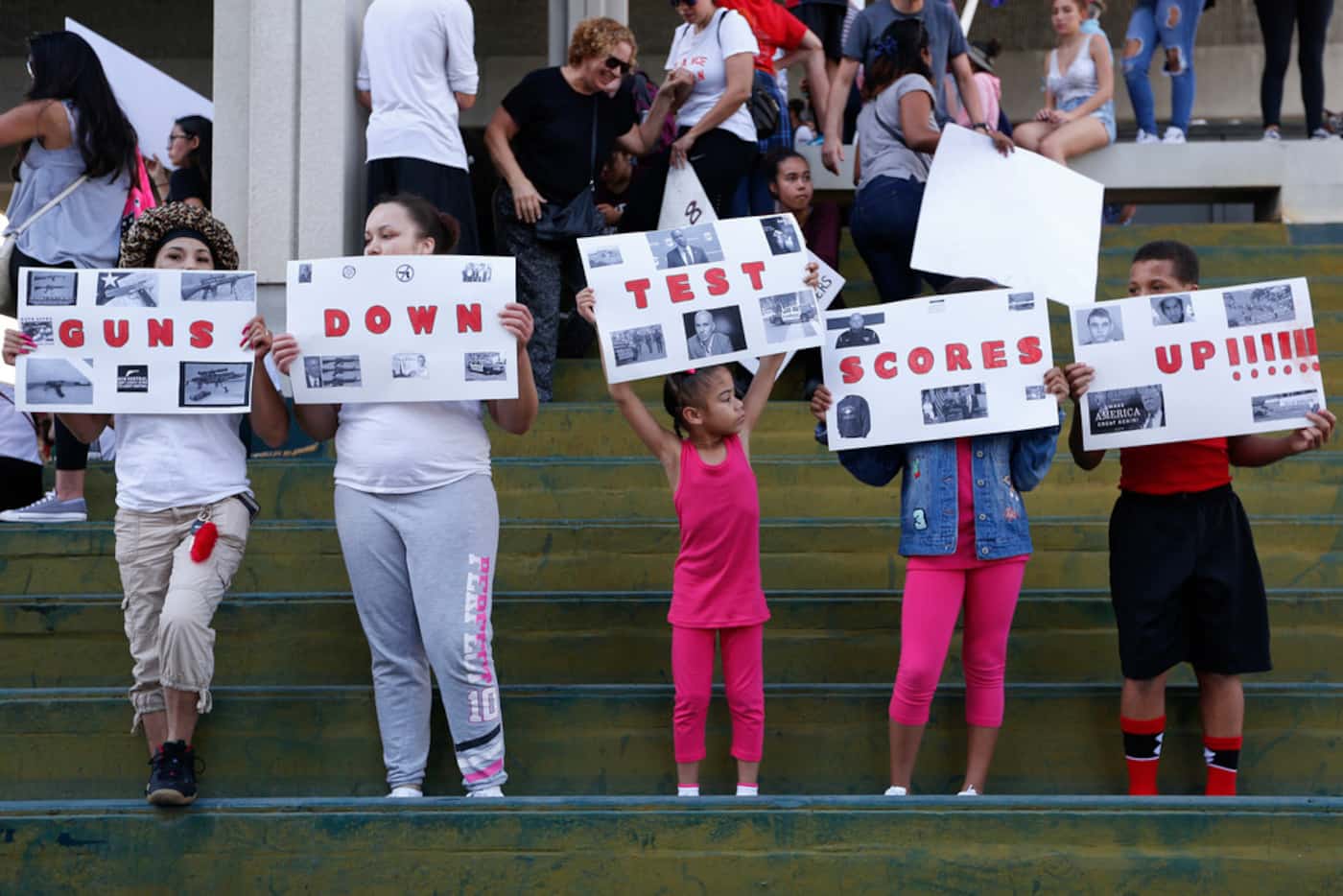 A group of people hold signs that read 'Guns Down Test Scores UP' during a protest against...
