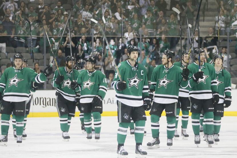 The Dallas Stars raise their sticks to acknowledge their fans as they skate off the ice...