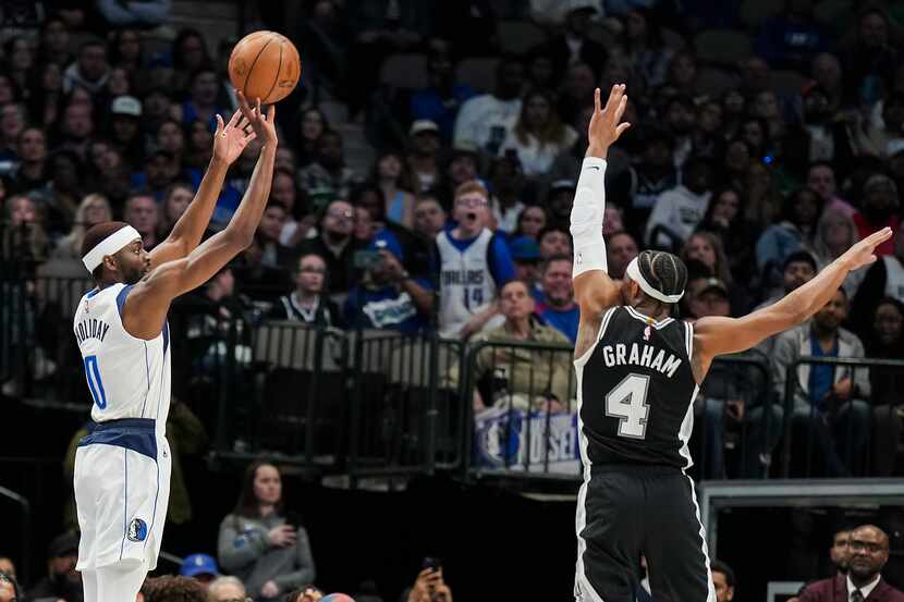Dallas Mavericks forward Justin Holiday (0) shoots a 3-pointer over San Antonio Spurs guard...