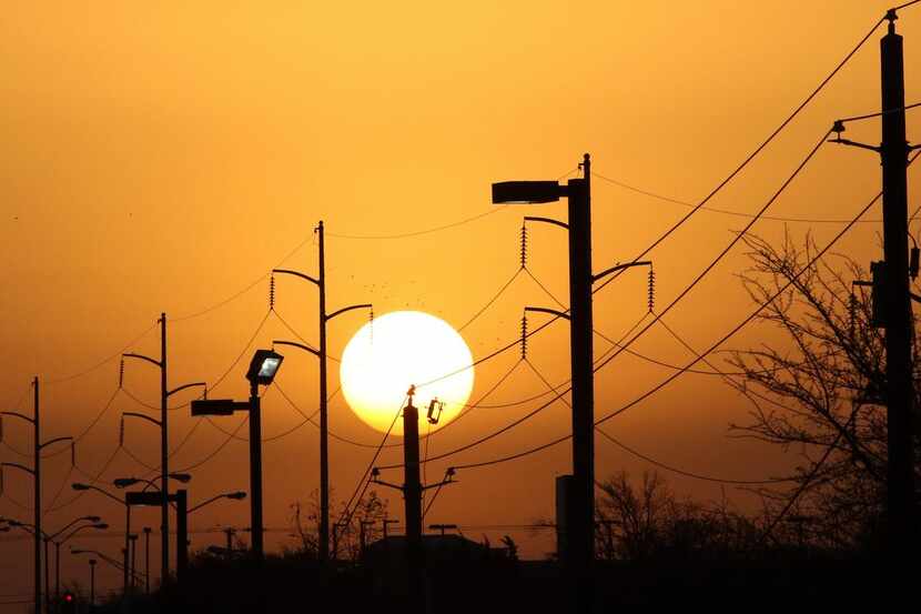  Overhead power lines and light poles are silhouetted as the morning sun rises over Camp...