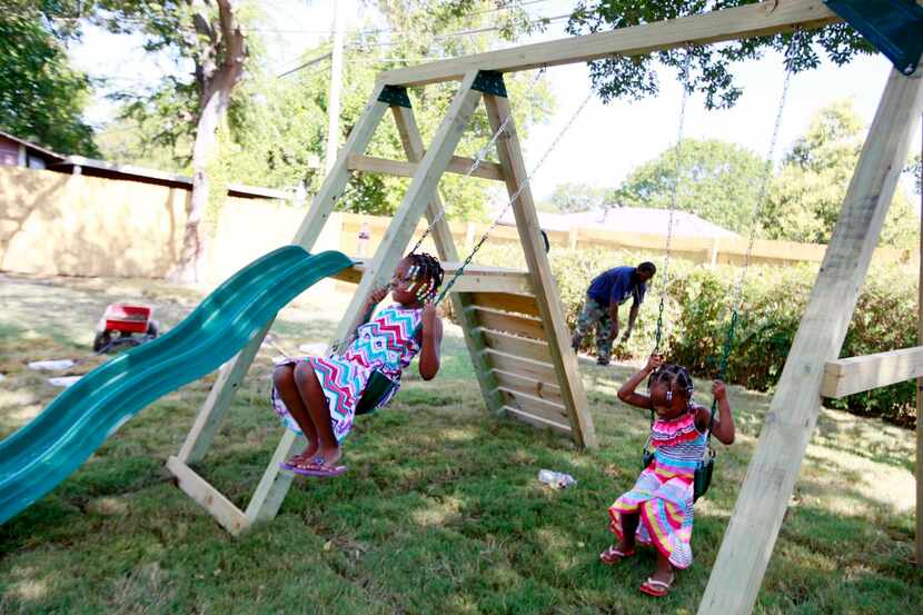 
Anaijah McQueen (left), 7, with her sister, Iquana McQueen, 4, play on a swing and slide...