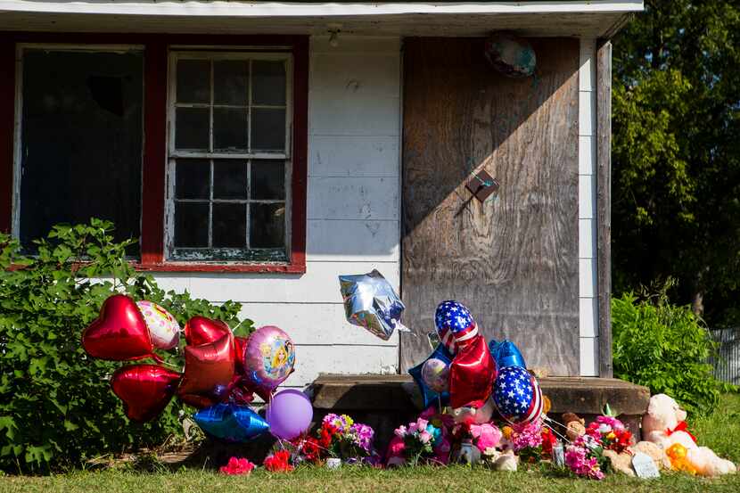 Memorial balloons and flowers wave in the wind at a home in the 2200 block of East Kiest...
