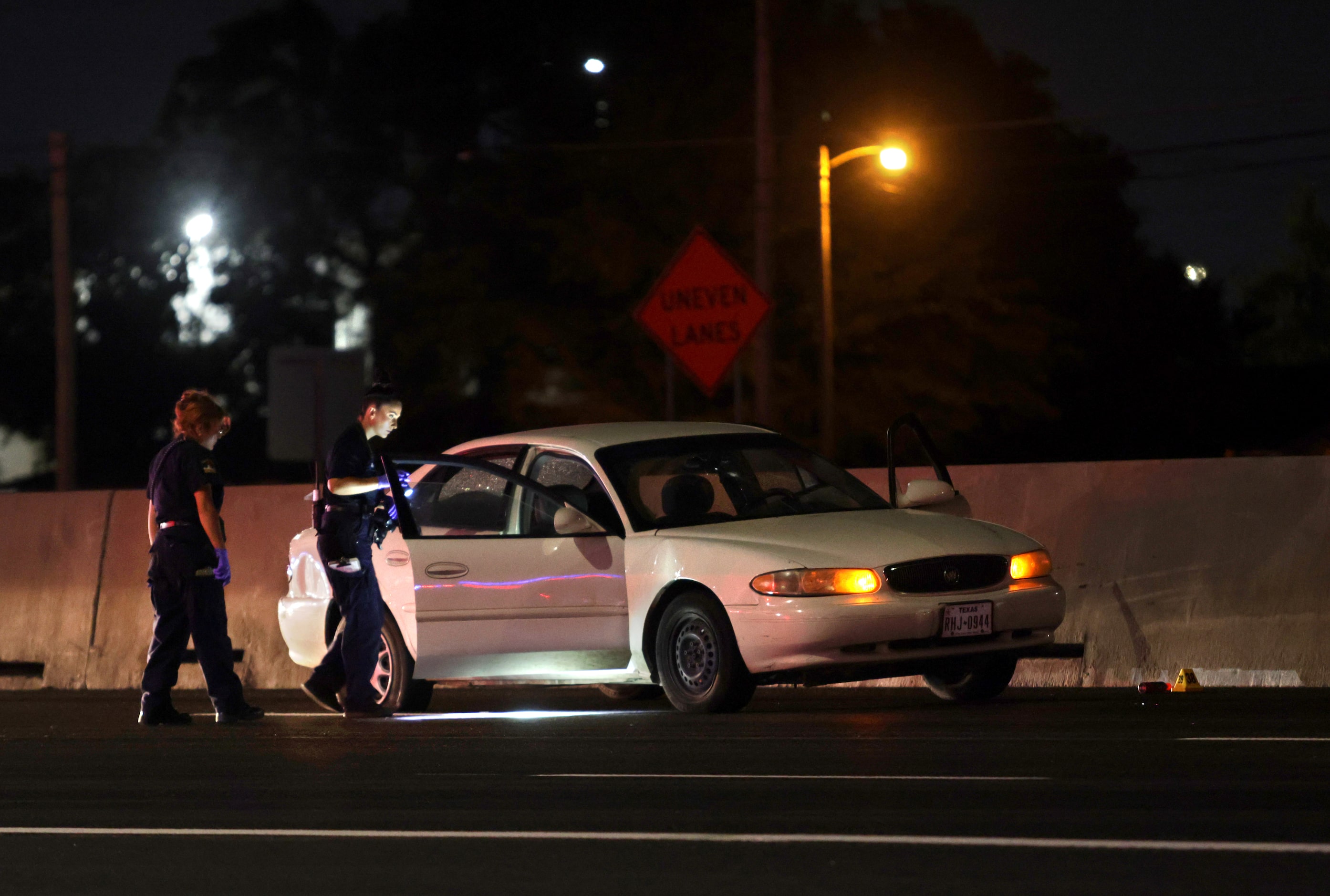 Officers examine a murder suspect's white Buick sedan for evidence in Lewisville, TX, on Aug...