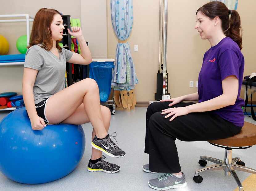 
Physical therapist Lara Trevett (right) leads Haley Holmes, 16, in a hip and core exercise...