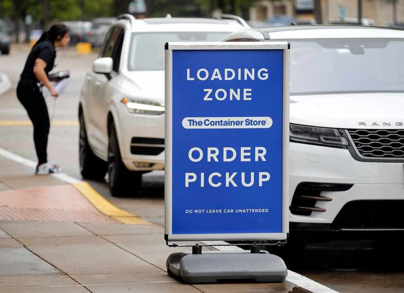 An employee of The Container Store speaks to a customer waiting in the curbside pickup line,...