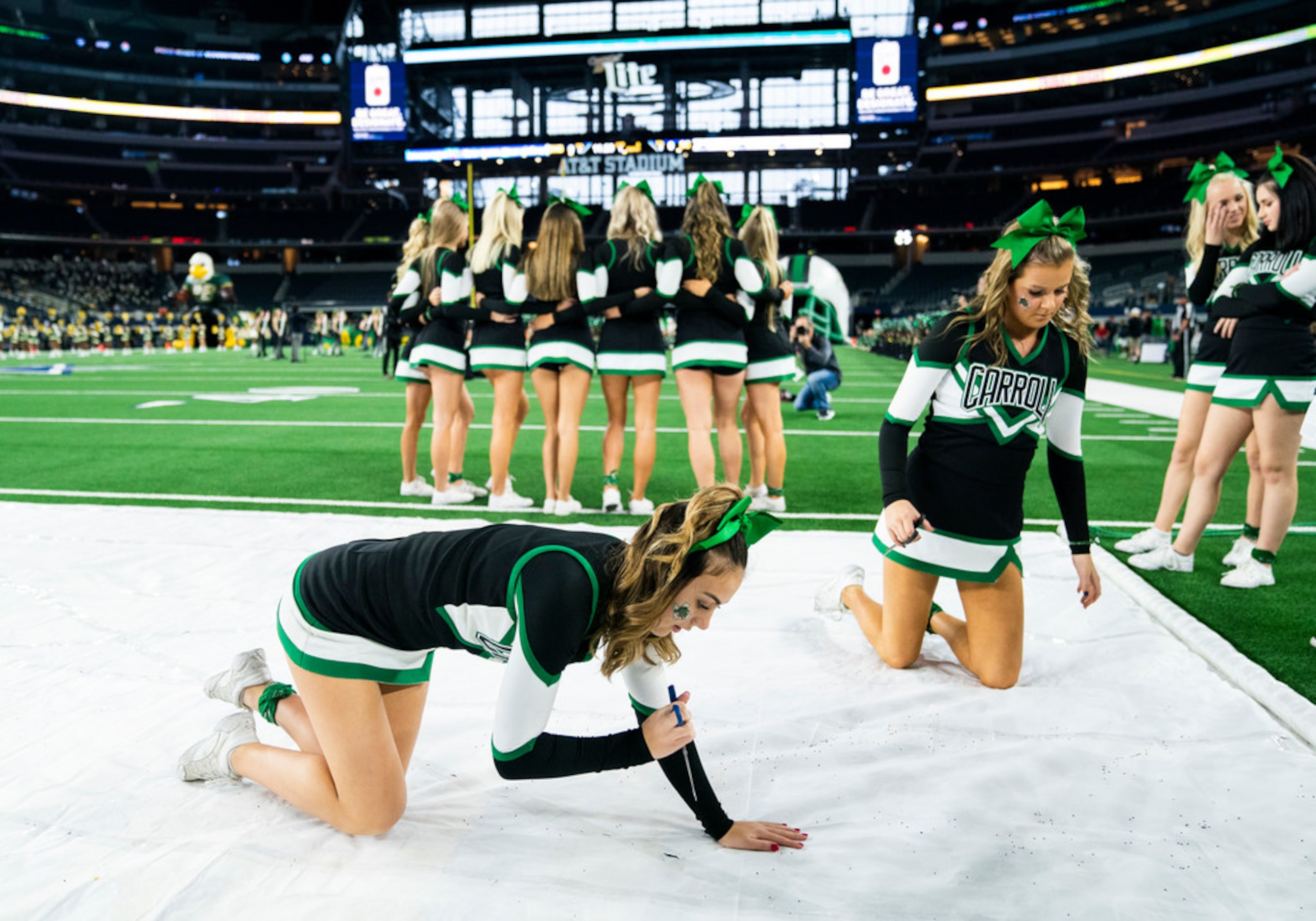 Southlake Carroll cheerleaders prepare a banner for the team to run through before a Class...