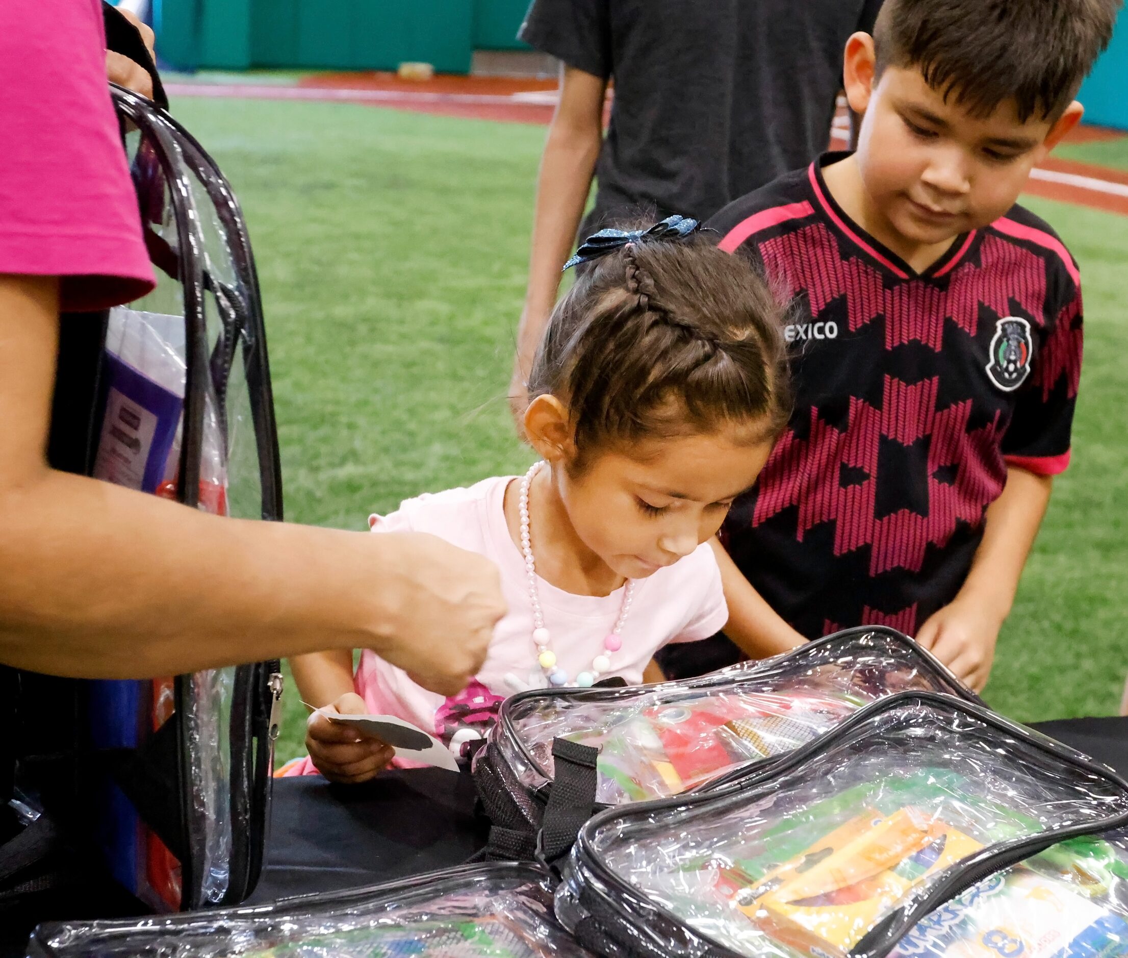 Renata Sarinana (center), 5, looks alongside Mateo Sarinana, 7, at the school supplies in...