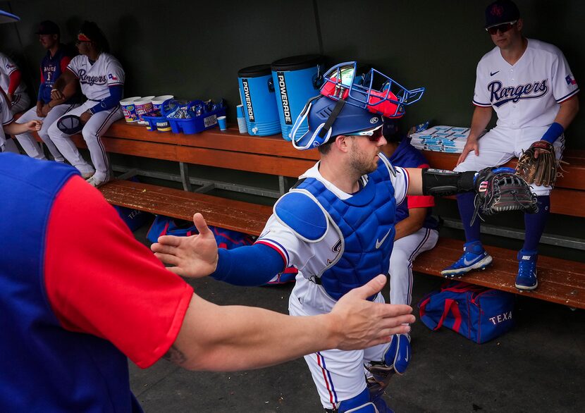 Texas Rangers catcher Mitch Garver slaps hands with teammates catcher Jonah Heim (left) and...