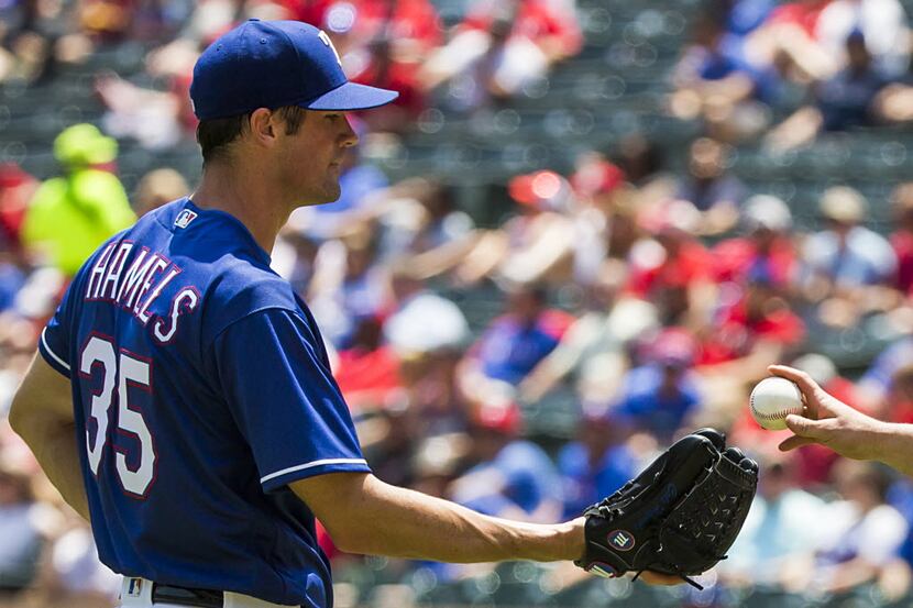 Texas Rangers starting pitcher Cole Hamels gets a new ball from catcher Bobby Wilson after...