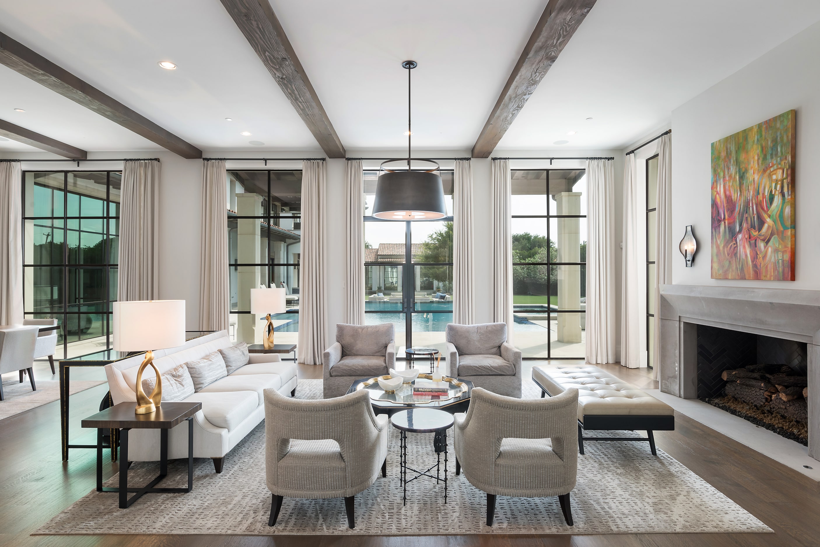 Living room with windows overlooking the backyard on the far end, chairs and couches...