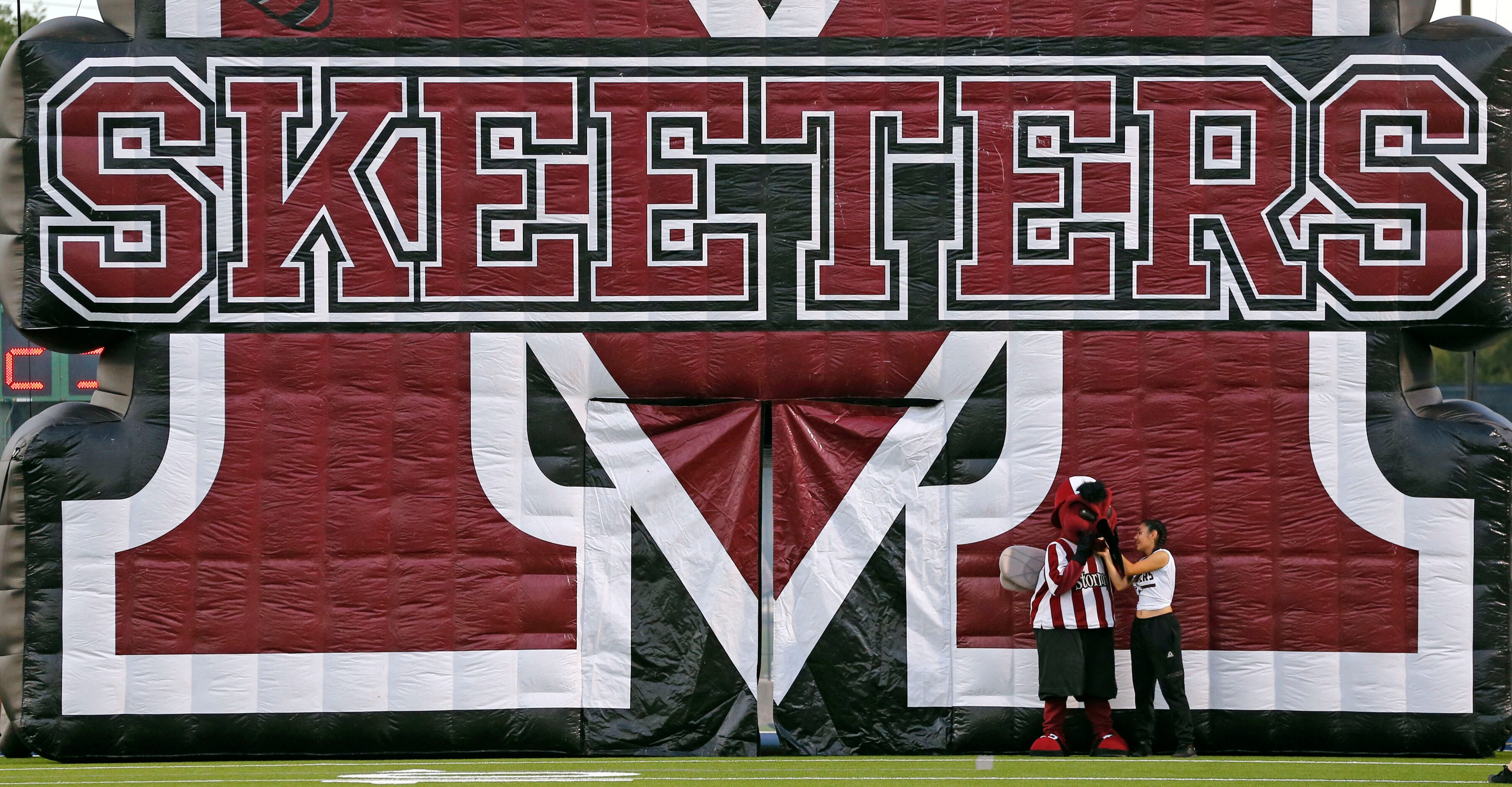 The Mesquite High mascot and handler make a wardrobe adjustment before the start of a high...