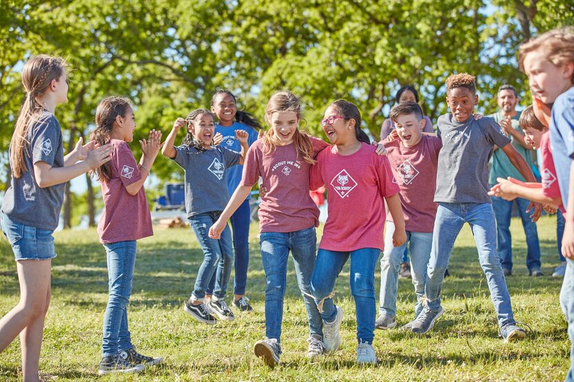 A group of cub scouts compete in a "three-legged race" together in a local park.