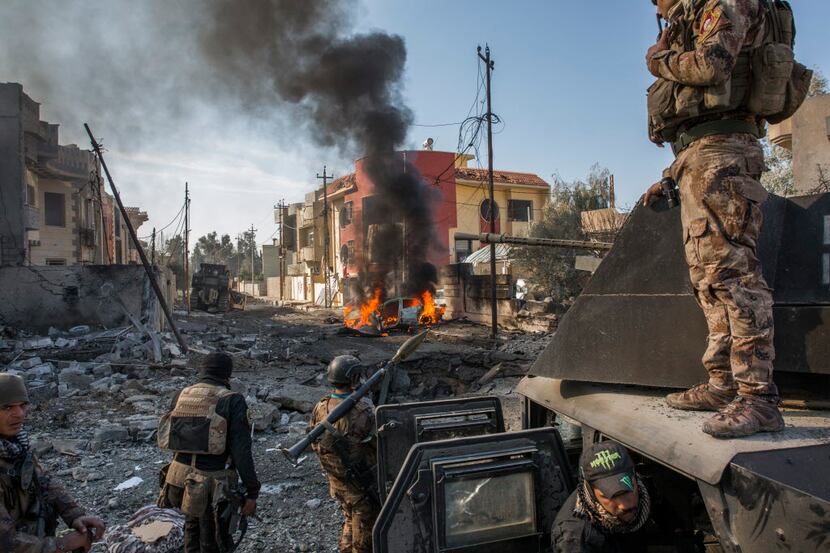 Iraqi Special Operations soldiers survey the aftermath of a suicide car bomb that managed to...