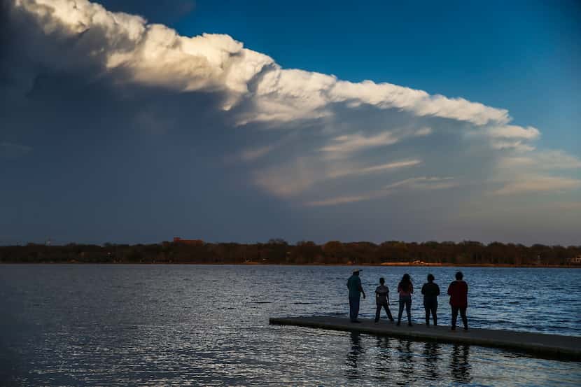 People watch passing clouds from a dock at White Rock Lake on Sunday afternoon, March 24,...