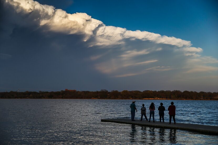 People watch passing clouds from a dock at White Rock Lake on Sunday afternoon, March 24,...