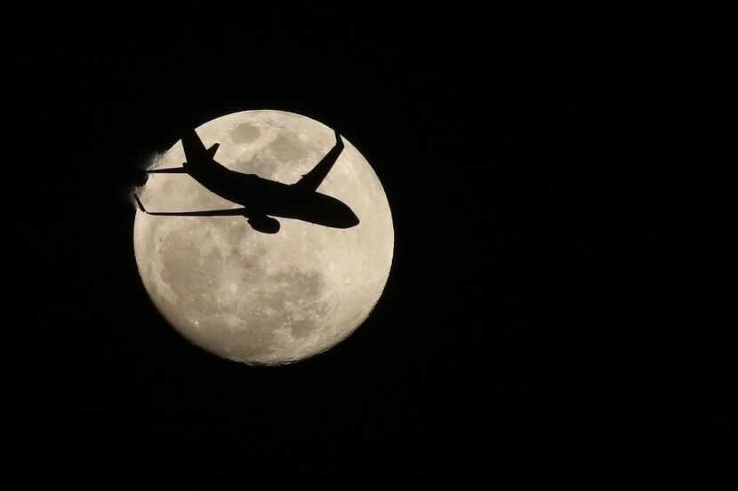 A Southwest jet is silhouetted against the moon after taking off from Love Field on Monday...