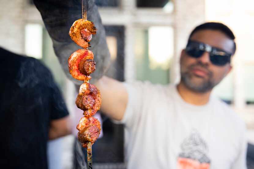 Zahid Ahmad takes shrimp and beef sausage coated with a Halal BBQ Pitmasters rub out of the...