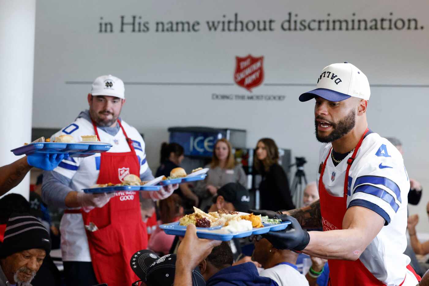 Dallas Cowboys’ Zack Martin (left) and QB Dak Prescott serve Thanksgiving meals during...