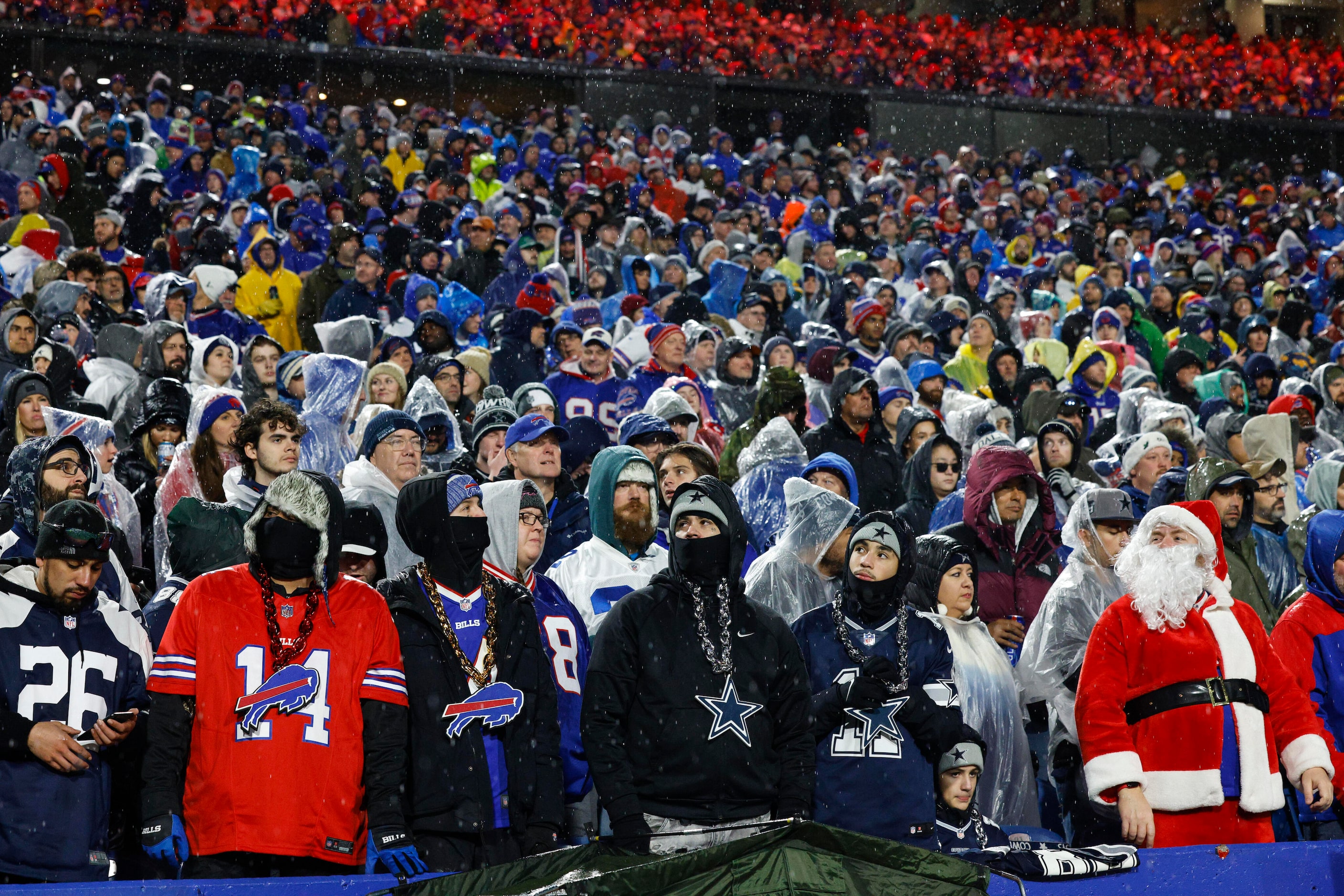 Fans stand in the rain during a timeout during the second half of an NFL game between the...