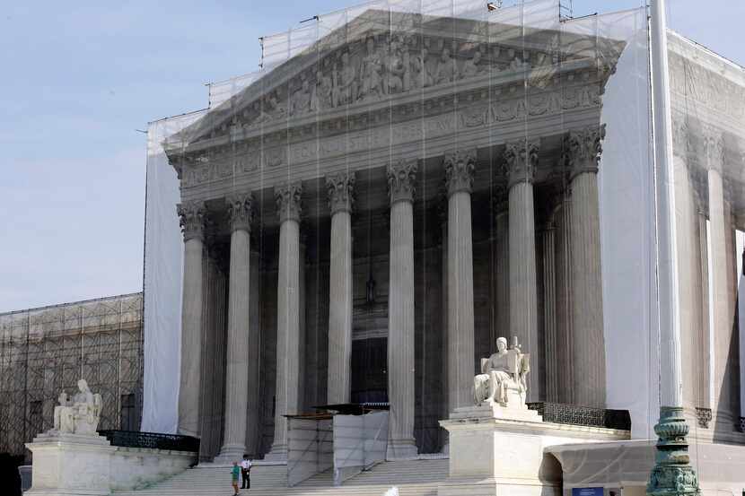 Workers cover the U.S. Supreme Court building in Washington Thursday, Sept. 27, 2012, with a...