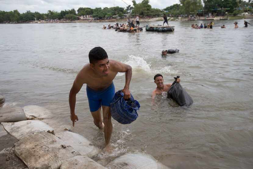 Central American migrants reach the shore on the Mexican side of the Suchiate River after...