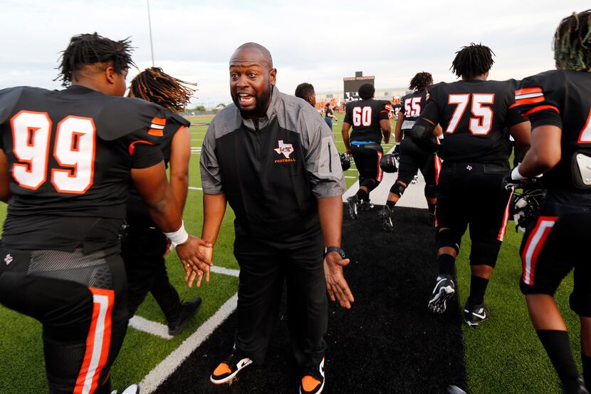 Lancaster head coach Christopher Gilbert slaps hands with his players after the team's...