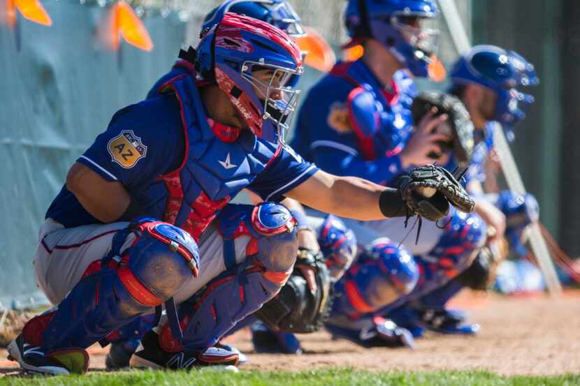 Texas Rangers catchers line up in the bullpen during a spring training workout at the team's...