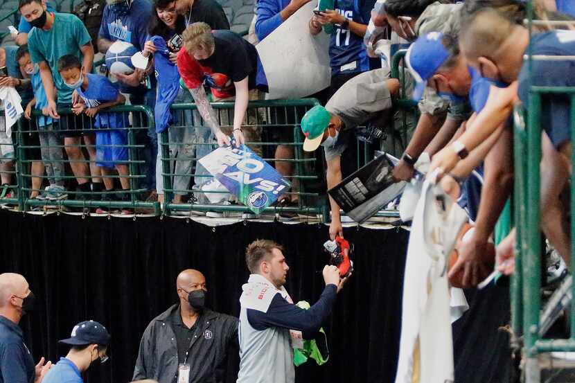 Dallas Mavericks guard Luka Doncic (77) autographs a shoe for one of the fans after the...