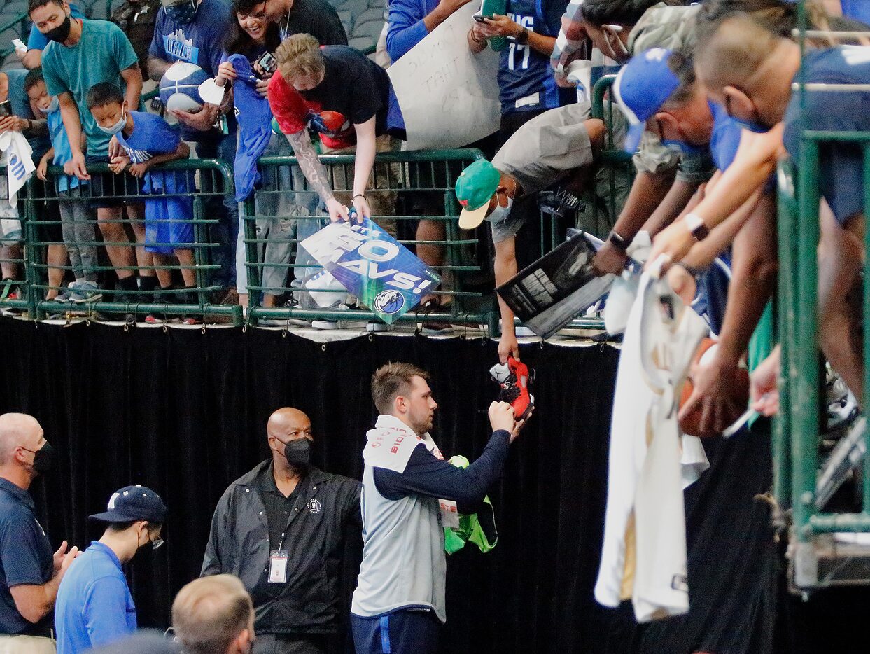 Dallas Mavericks guard Luka Doncic (77) autographs a shoe for one of the fans after the...