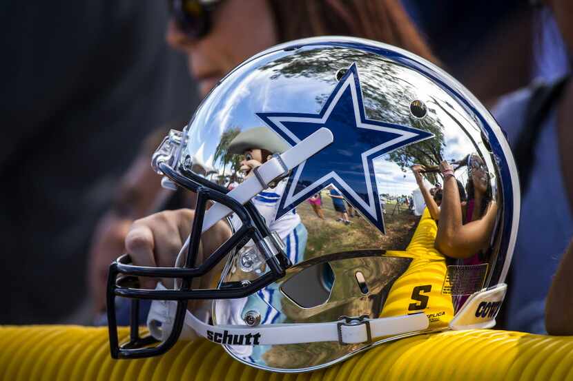 Dallas Cowboys mascot Rowdy is reflected in a fan's helmet as they wait for the team to take...