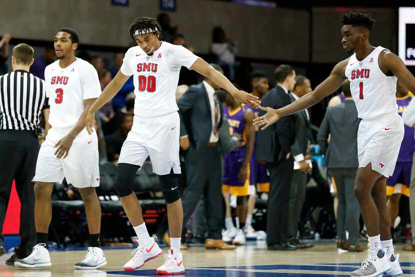 SMU guard Shake Milton (1) and forward Ben Moore (00) touch hands as they walk to the bench...