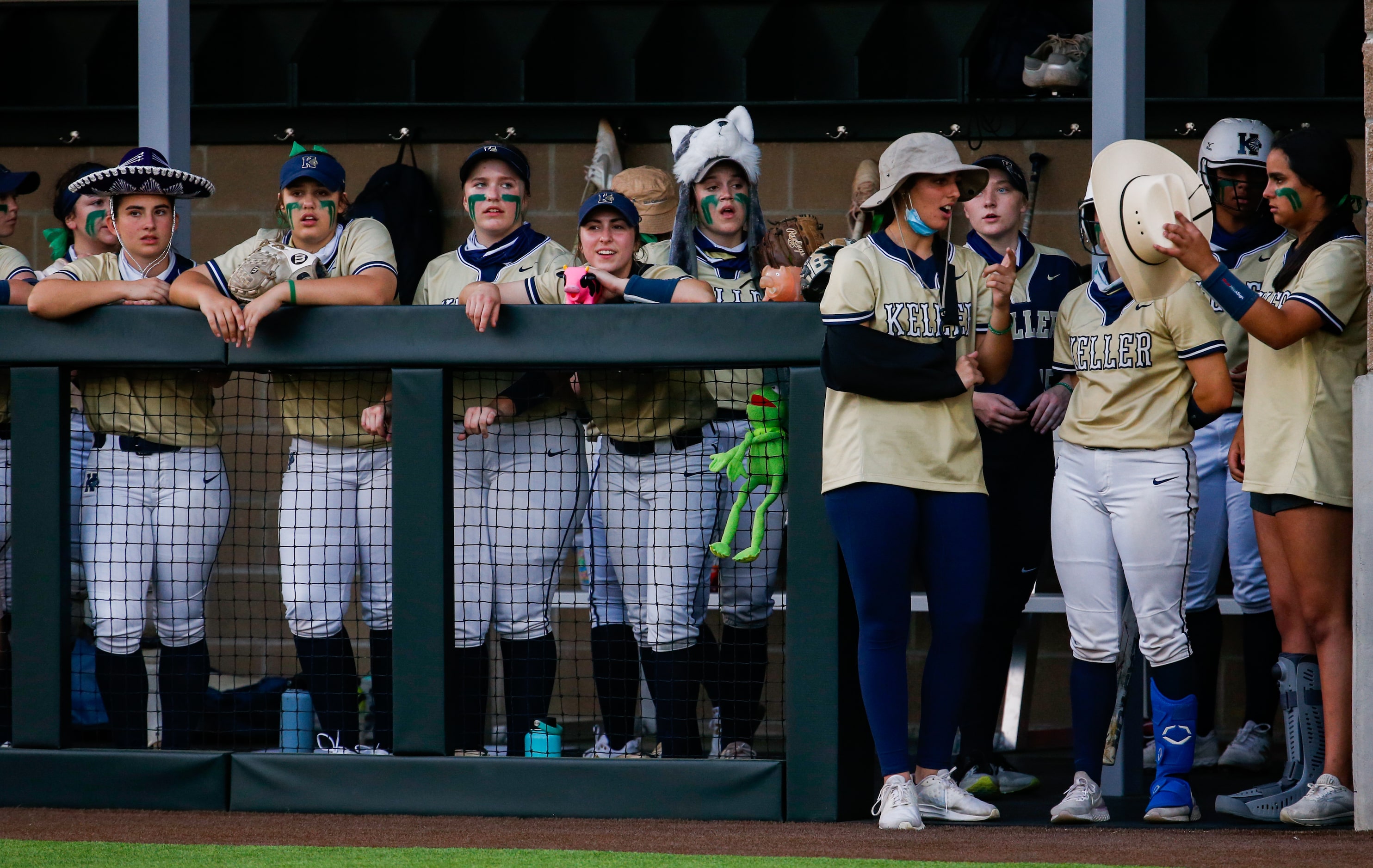 Keller players wear random hats on the sideline of a nondistrict softball game against...