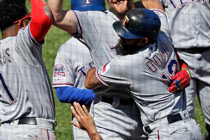 Texas Rangers' Hunter Pence, center, is congratulated by Rougned Odor (12) and Elvis Andrus...