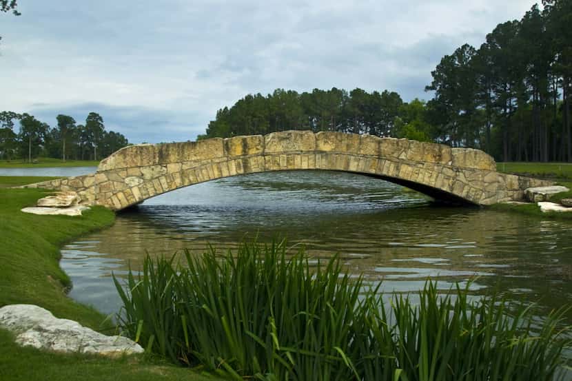 A stone bridge crosses the water feature near the par 4, No. 18 at Whispering Pines Golf...
