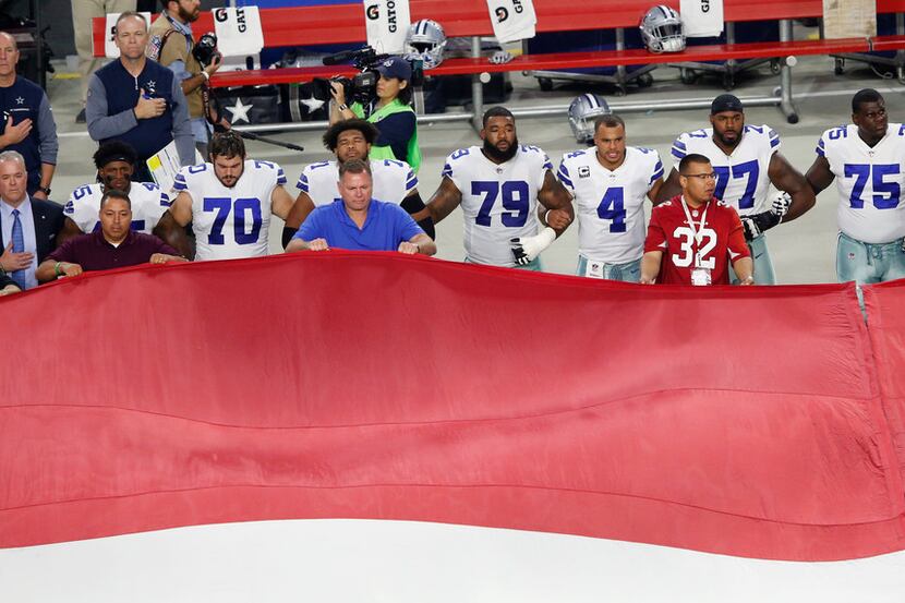 Dallas Cowboys link arm in arm during the National Anthem prior to the start of a game...