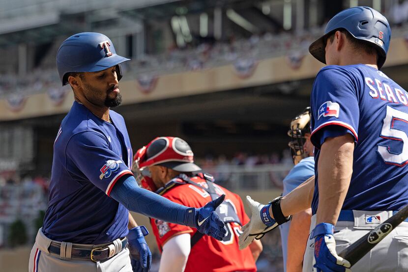 Texas Rangers' Marcus Semien, left, high-fives teammate Corey Seager, right, after hitting a...