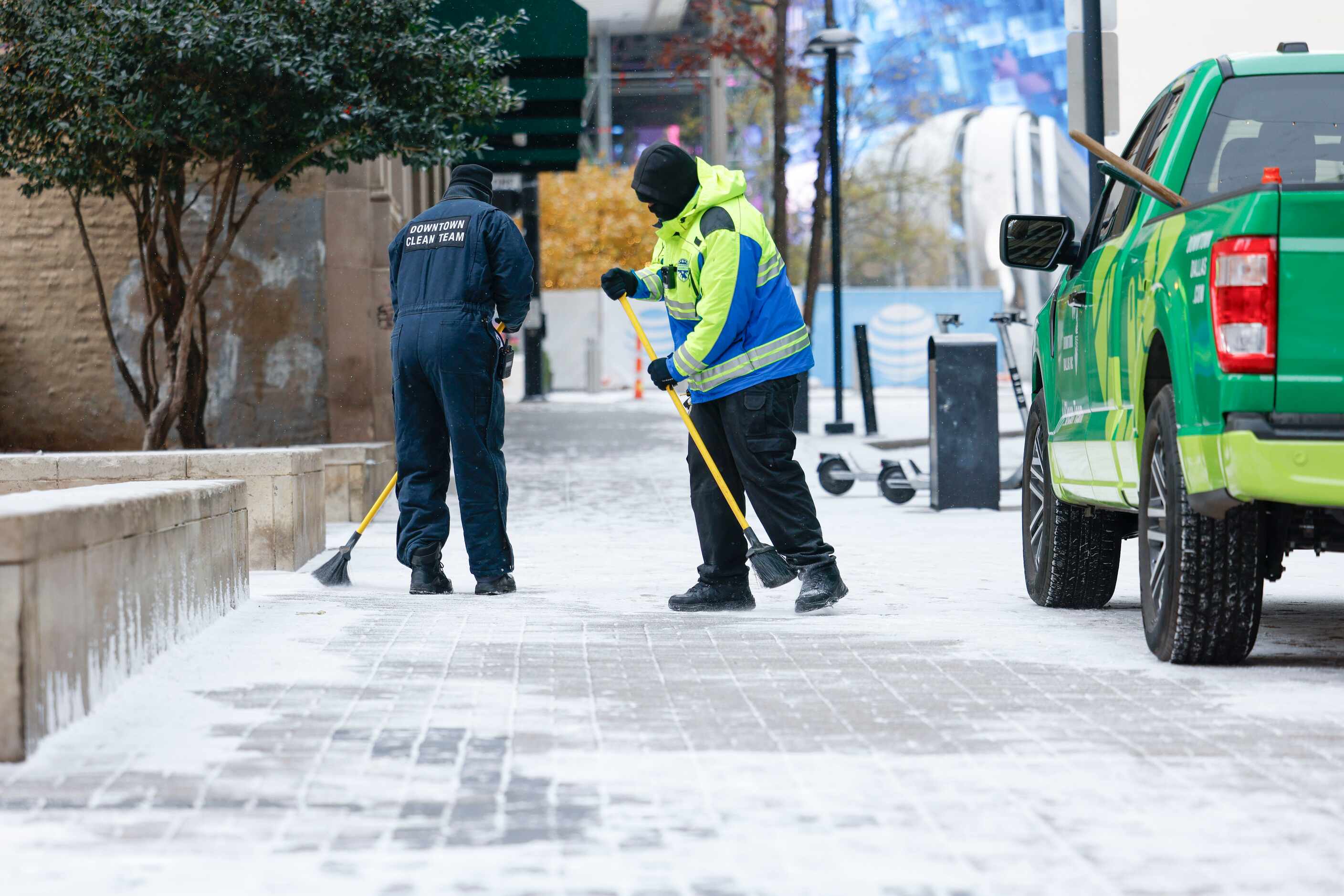 Downtown Dallas Inc. cleaning crews brush off the snow from the sidewalk on Monday, Jan. 15,...