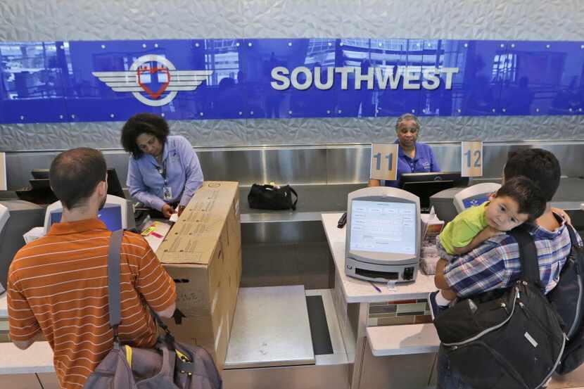 In this photo taken, June 5, 2014, travelers check in at a Southwest Airlines ticket counter...