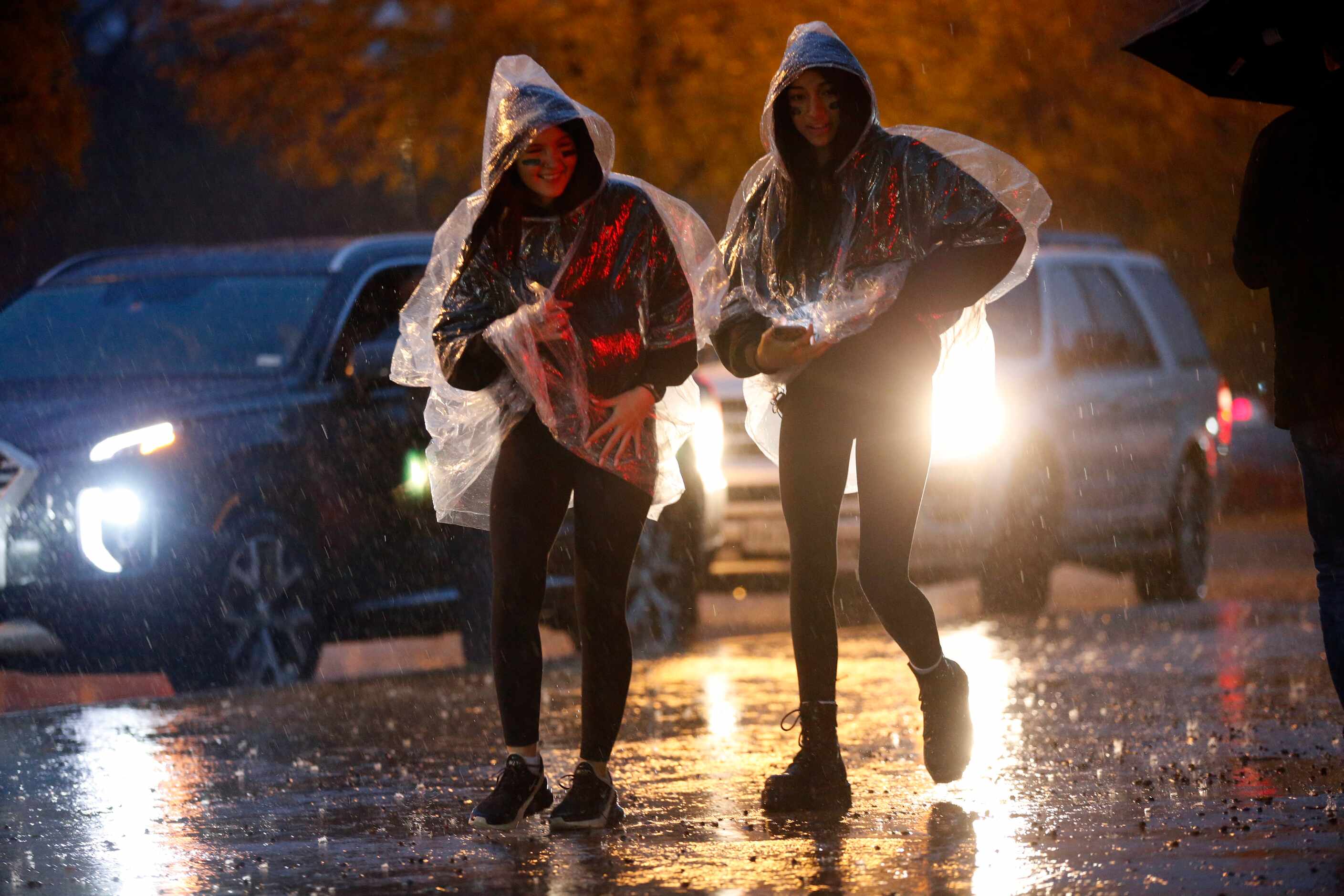 Southlake Carroll Dragon fans Lauren Llamas and Sarah Nichols (left) race through the rain...