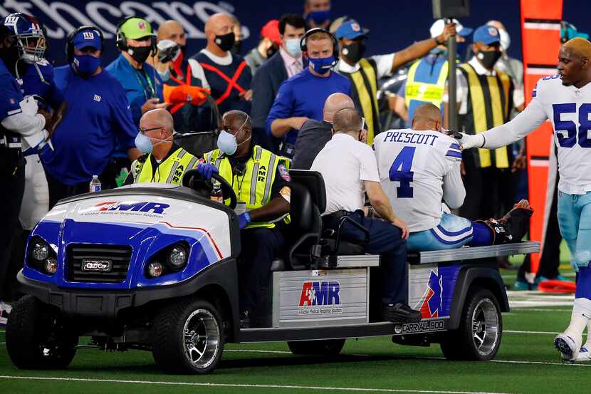 Cowboys defensive end Aldon Smith (58) comforts quarterback Dak Prescott (4) as he's carted...