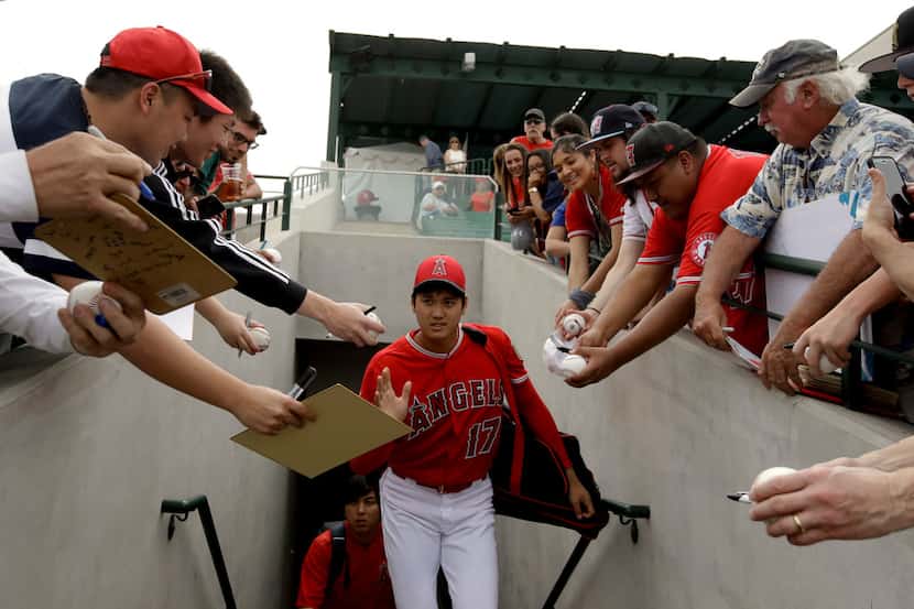 Fans try for a autograph from Los Angeles Angels starting pitcher Shohei Ohtani, of Japan,...