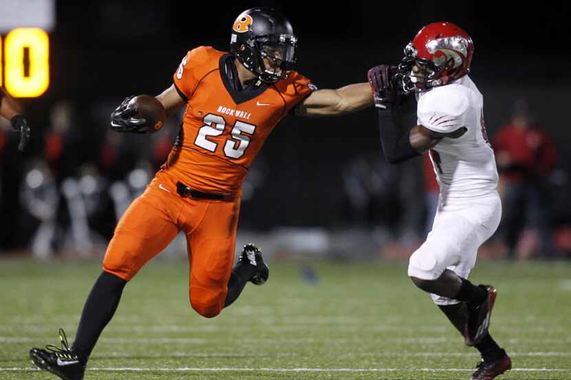 Rockwall running back Chris Warren (25) stiff arms Mesquite Horn defensive back J.R. Hall...