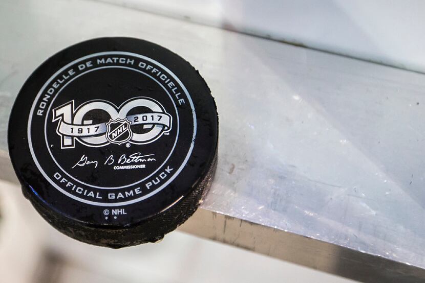 A puck rests behind the boards near the bench during the third period of an NHL hockey game...