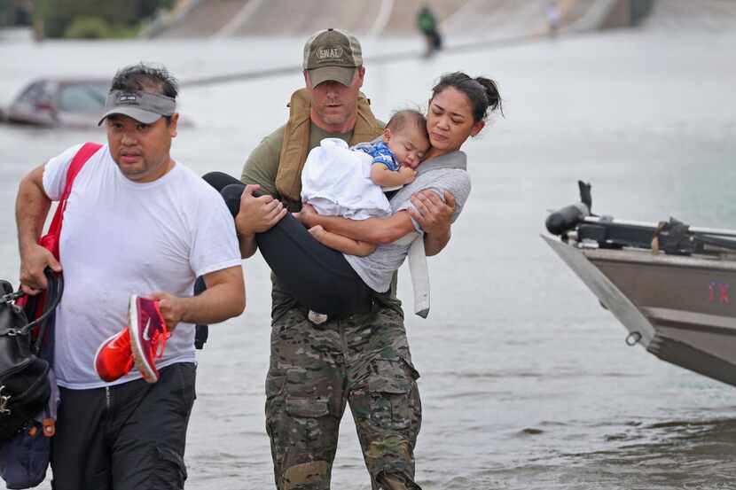 El oficial del Houston SWAT Daryl Hudeck carga a Catherine Pham y su hijo de 13 meses Aiden...
